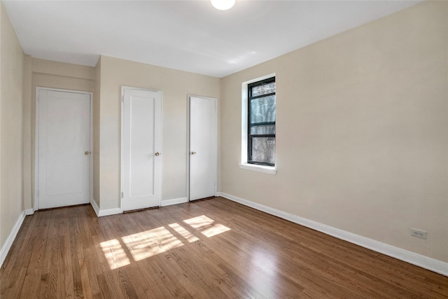 unfurnished bedroom featuring wood finished floors and baseboards