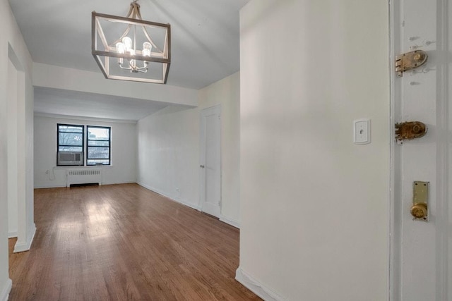 interior space with a notable chandelier, radiator heating unit, wood finished floors, and baseboards