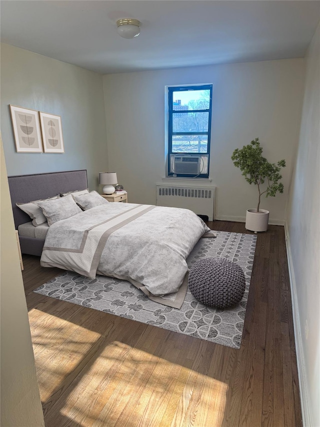 bedroom with radiator heating unit, wood finished floors, and baseboards