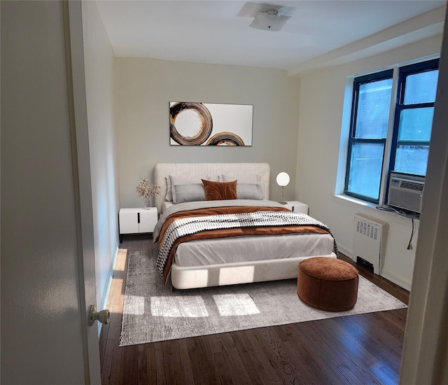 bedroom featuring baseboards, radiator heating unit, cooling unit, and wood finished floors