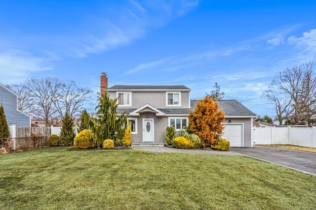 traditional-style home with aphalt driveway, an attached garage, fence, a chimney, and a front yard