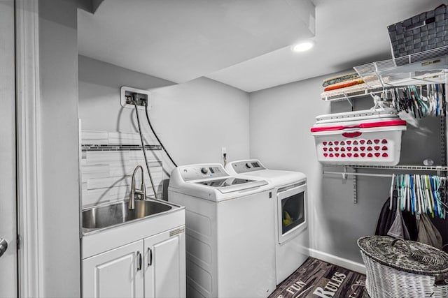 clothes washing area featuring washing machine and dryer, a sink, baseboards, cabinet space, and dark wood-style floors