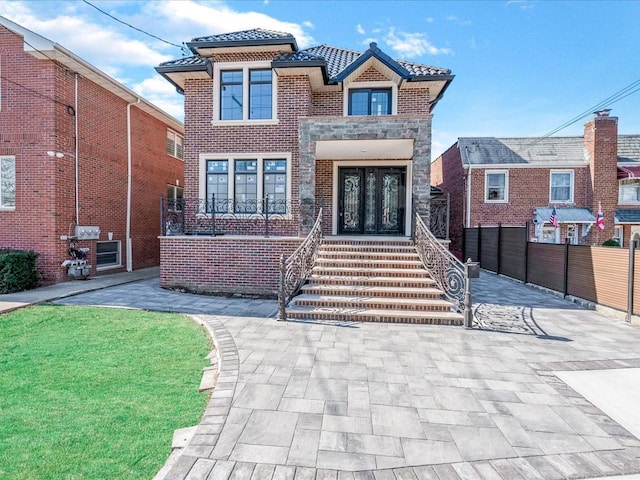 view of front of property featuring a tiled roof, french doors, and stone siding