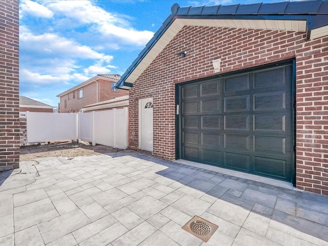 garage featuring fence and concrete driveway