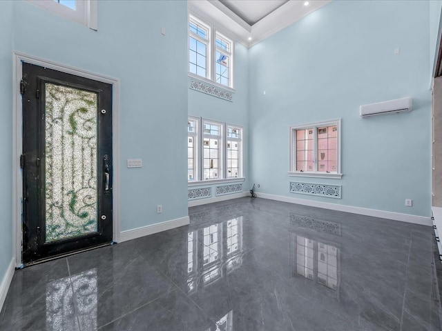 entrance foyer with a wall mounted air conditioner, a towering ceiling, and baseboards