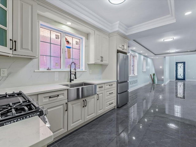 kitchen featuring crown molding, light countertops, freestanding refrigerator, white cabinetry, and a sink