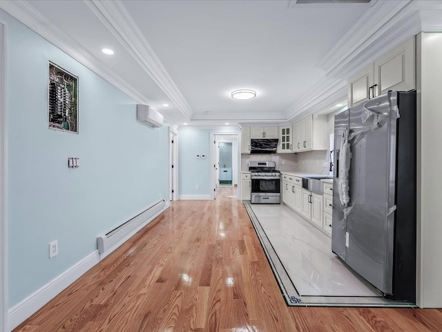 kitchen with light wood-style flooring, ornamental molding, a wall mounted air conditioner, baseboard heating, and stainless steel appliances