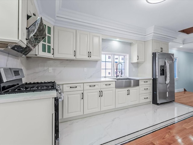 kitchen featuring decorative backsplash, appliances with stainless steel finishes, ornamental molding, white cabinetry, and a sink