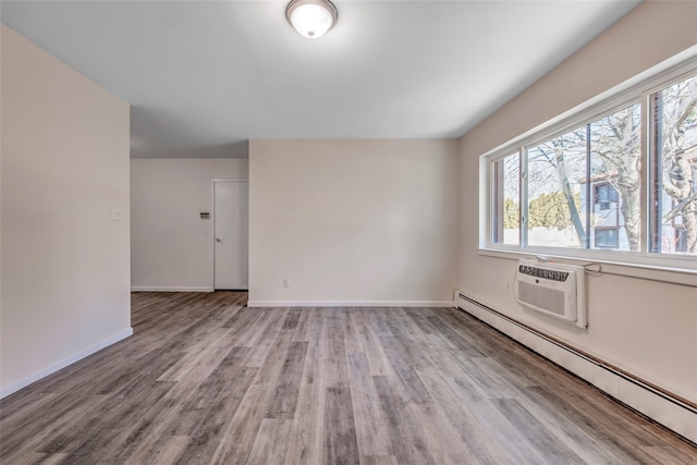 unfurnished room with a baseboard radiator, wood finished floors, and baseboards