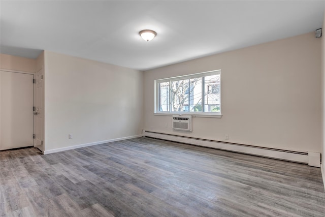 empty room featuring baseboards, a baseboard heating unit, wood finished floors, and a wall mounted AC