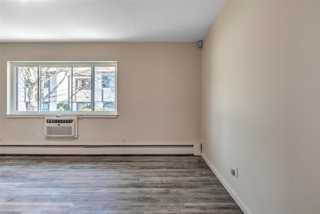 empty room with a baseboard heating unit, a wall unit AC, baseboards, and wood finished floors