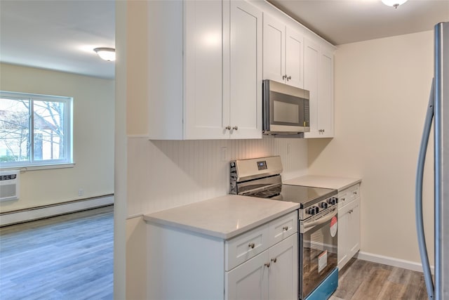 kitchen featuring baseboard heating, stainless steel appliances, light countertops, light wood-style floors, and white cabinetry