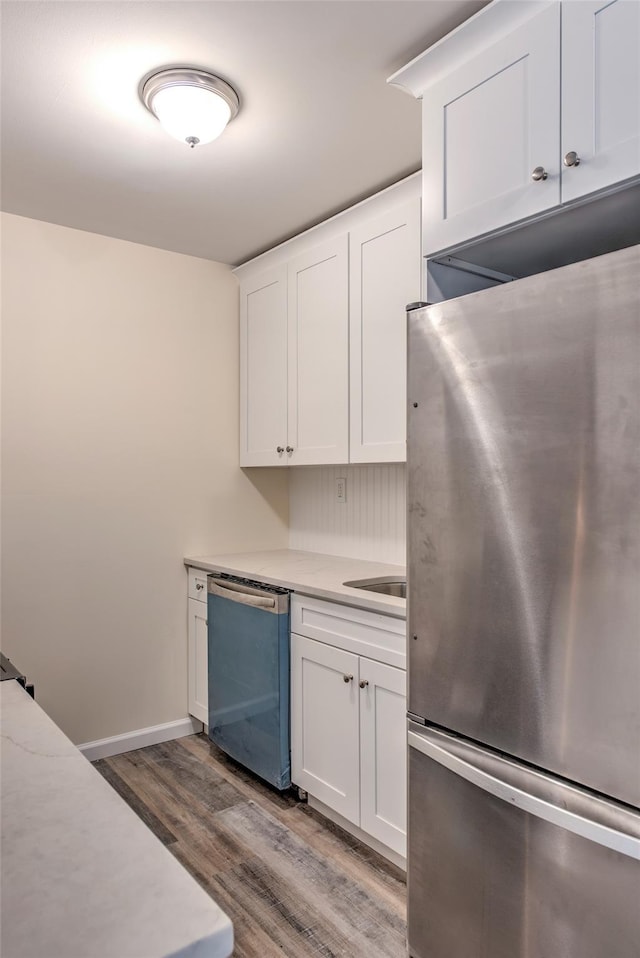 kitchen featuring stainless steel appliances, white cabinets, baseboards, and wood finished floors