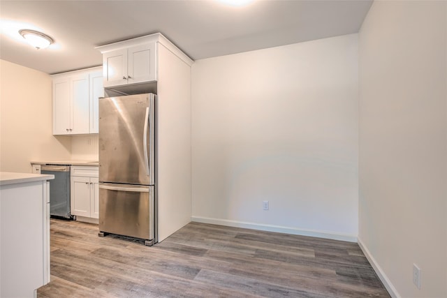 kitchen featuring stainless steel appliances, light wood-type flooring, light countertops, and white cabinets