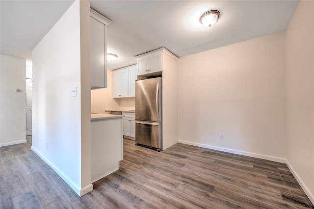 kitchen with baseboards, white cabinetry, wood finished floors, and freestanding refrigerator