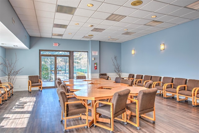 dining area with a paneled ceiling, a wainscoted wall, wood finished floors, and french doors