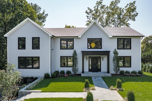 modern farmhouse style home featuring a shingled roof and a front lawn