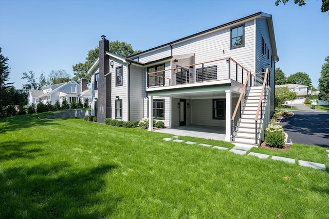 rear view of house with a patio, stairway, a chimney, and a lawn