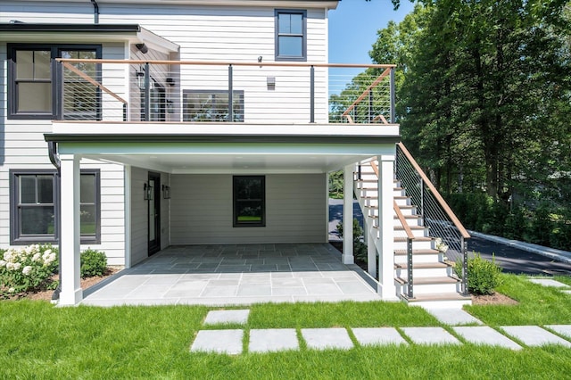 back of property featuring a carport, a balcony, and stairs