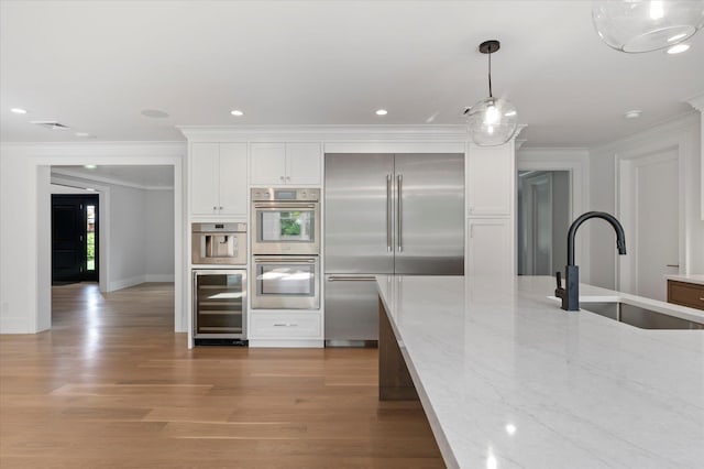 kitchen with wine cooler, light wood finished floors, stainless steel appliances, white cabinets, and a sink