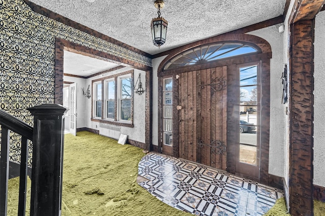 entryway featuring baseboards, a healthy amount of sunlight, a textured ceiling, and radiator heating unit