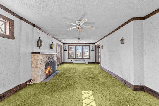 unfurnished living room with a textured ceiling, a textured wall, a stone fireplace, and radiator heating unit