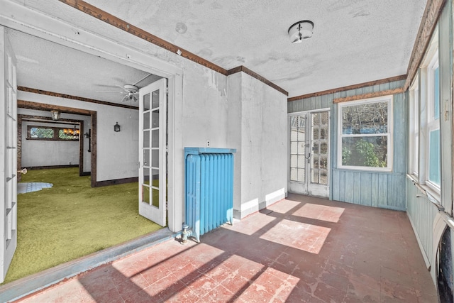 unfurnished sunroom featuring a ceiling fan and radiator heating unit