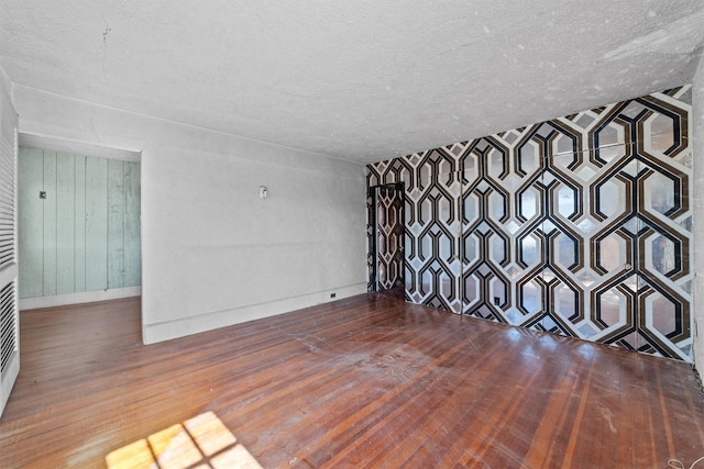 unfurnished living room with a textured ceiling, baseboards, and hardwood / wood-style floors