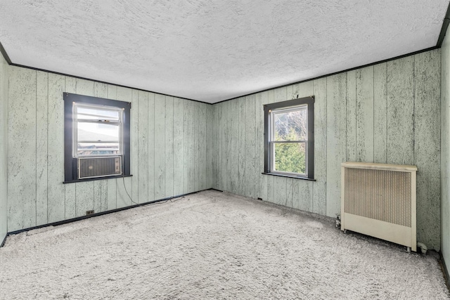 empty room with carpet, radiator, cooling unit, and a textured ceiling