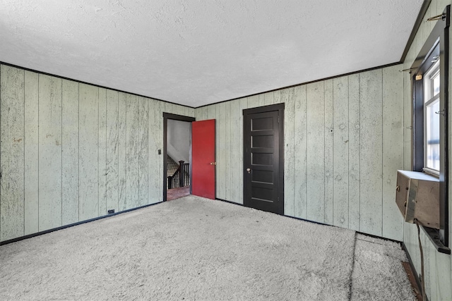 unfurnished bedroom with a textured ceiling, ornamental molding, and carpet flooring