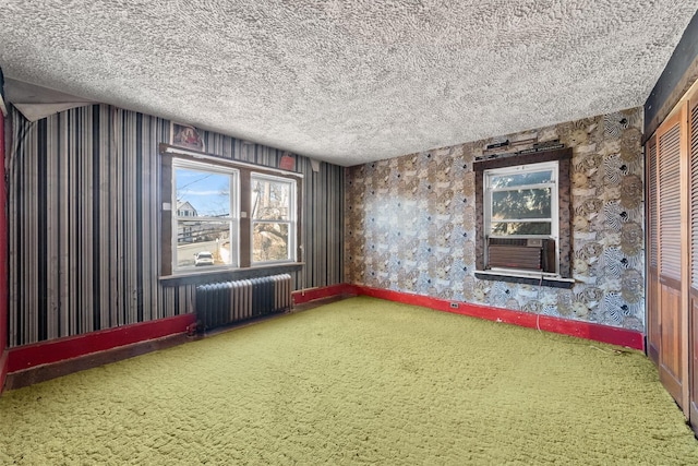 carpeted spare room with cooling unit, radiator, a textured ceiling, and baseboards