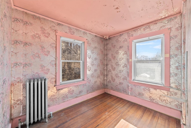 empty room with radiator, baseboards, hardwood / wood-style floors, and wallpapered walls