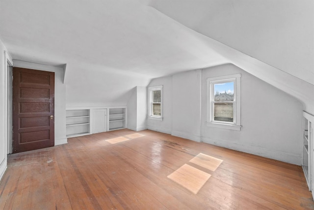 additional living space with lofted ceiling, wood-type flooring, and built in features