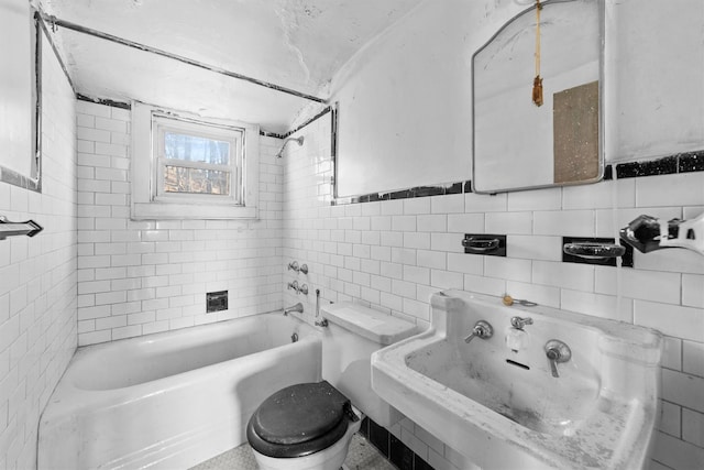 full bathroom with toilet, washtub / shower combination, a sink, and tile walls