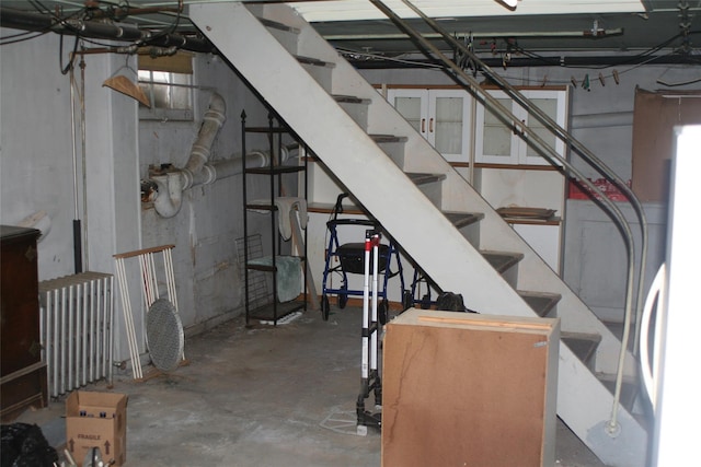 below grade area featuring refrigerator, radiator, and stairway