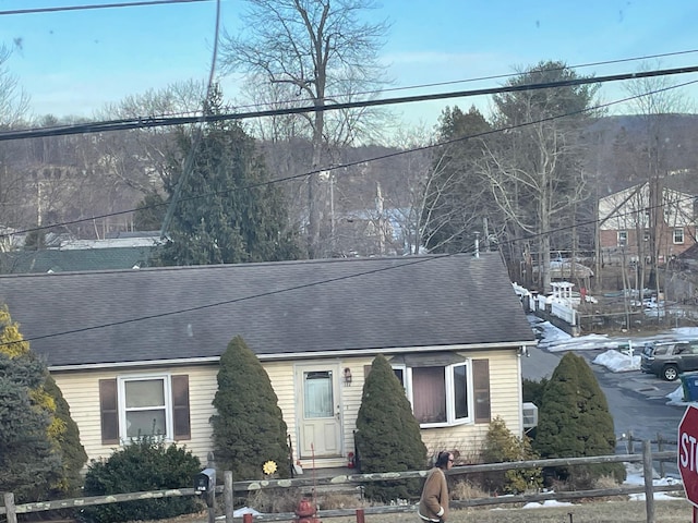 view of front of home featuring roof with shingles and fence