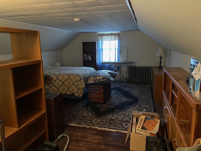 bedroom with vaulted ceiling, wood finished floors, and radiator