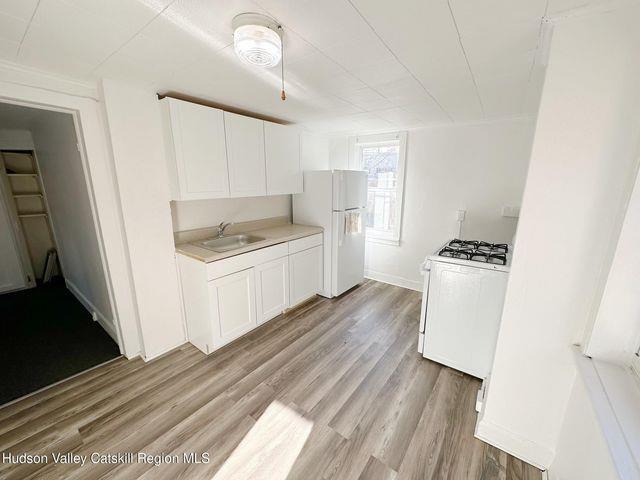 kitchen with white appliances, white cabinets, light countertops, light wood-style floors, and a sink