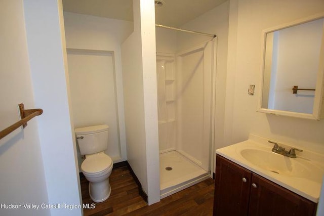 bathroom with vanity, wood finished floors, a shower stall, and toilet