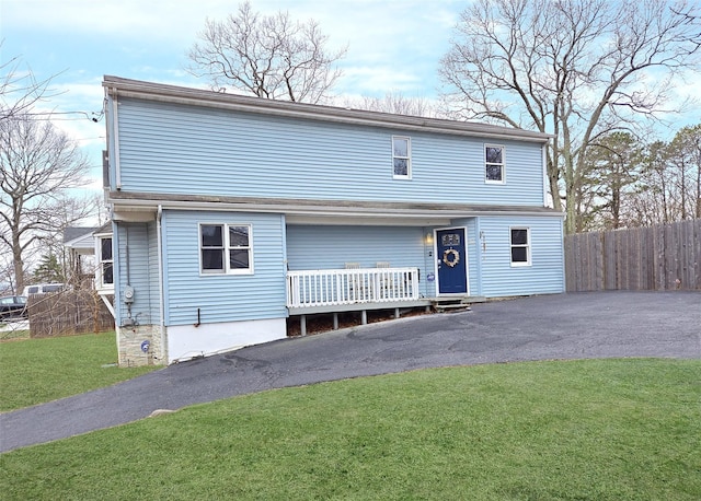 traditional-style house featuring a front yard, a porch, fence, and driveway