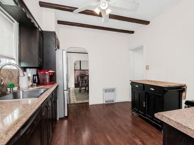 kitchen featuring arched walkways, dark wood finished floors, dishwasher, a sink, and beam ceiling