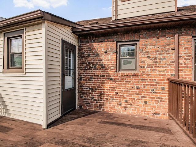 doorway to property featuring brick siding and a deck