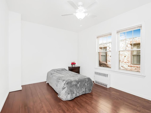 bedroom with radiator, a ceiling fan, baseboards, and dark wood-style flooring