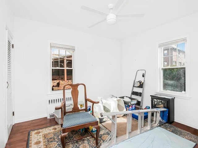 living area with dark wood-style floors, ceiling fan, baseboards, and radiator