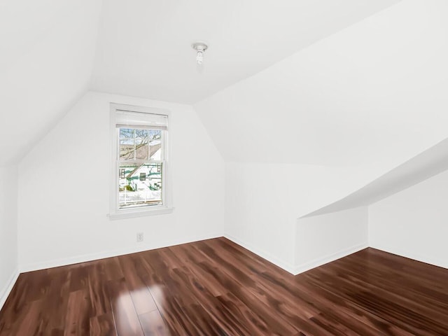 additional living space with dark wood-style floors, lofted ceiling, and baseboards