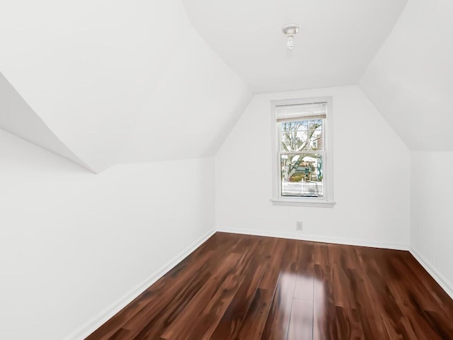 bonus room featuring lofted ceiling, baseboards, and dark wood-type flooring