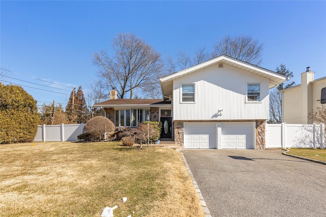 tri-level home featuring stone siding, a chimney, fence, and a front lawn