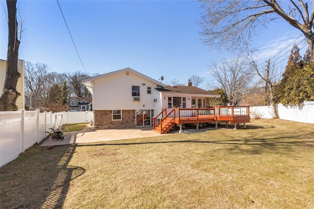 back of property with a fenced backyard, a deck, a lawn, and a patio