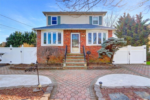 view of front of house with brick siding, fence, and a gate