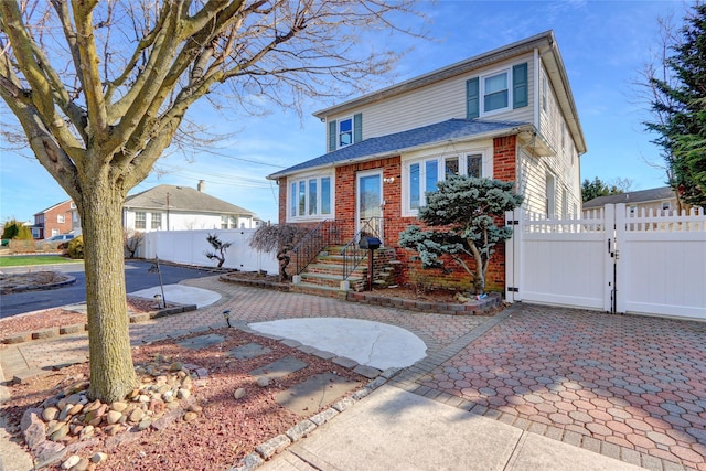 view of front of house with brick siding, a patio area, fence, and a gate